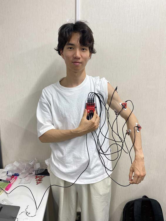 腕に筋電位センサと電気刺激パッドを装着して検証する香取賢佑